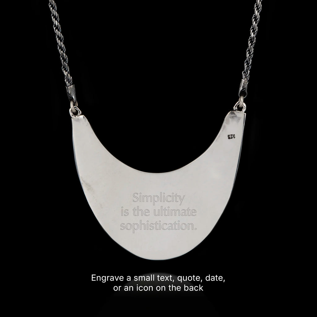 Silver necklace with a crescent-shaped pendant backside on a black background