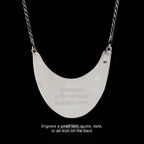 Silver necklace with a crescent-shaped pendant backside on a black background