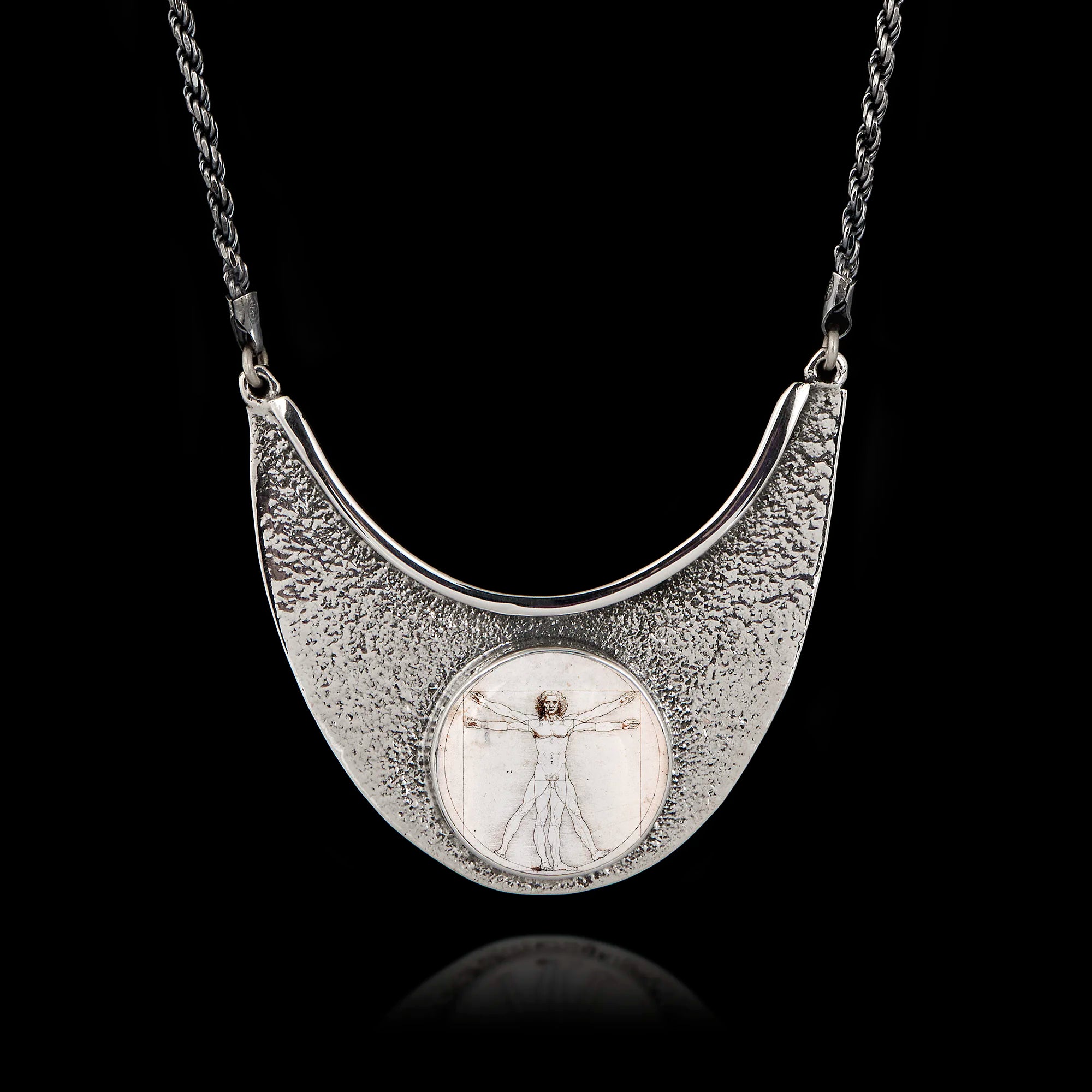 Unique 925 sterling silver statement necklace featuring a round ceramic Vitruvian Man by Da Vinci, set in a textured hammered silver crescent frame.