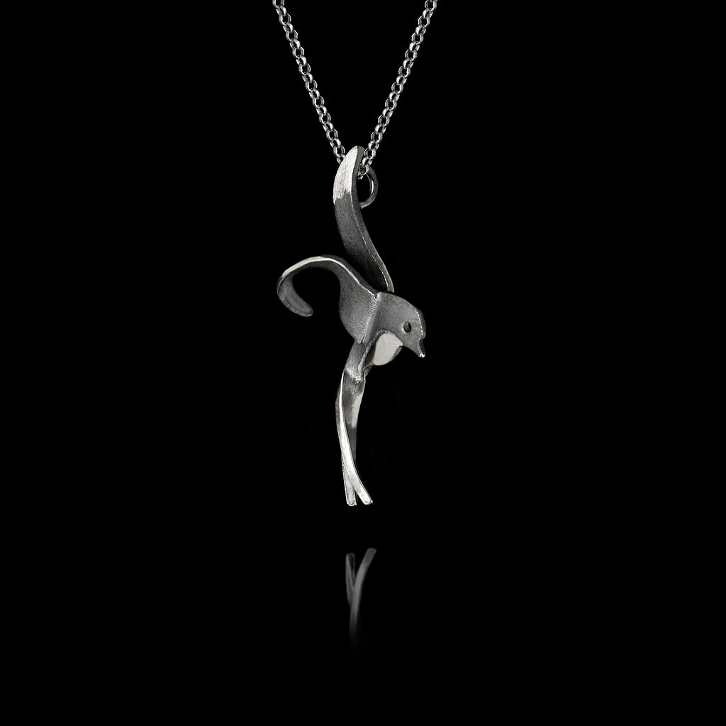 Side angle view of a handcrafted 925 sterling silver oxidised swallow pendant showing the fluid sculpted silhouette of a swallow in flight on a silver chain against a black background.