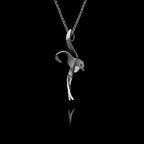Side angle view of a handcrafted 925 sterling silver oxidised swallow pendant showing the fluid sculpted silhouette of a swallow in flight on a silver chain against a black background.