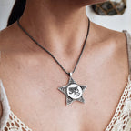 Star-shaped pendant necklace on a person wearing a beige lace top.