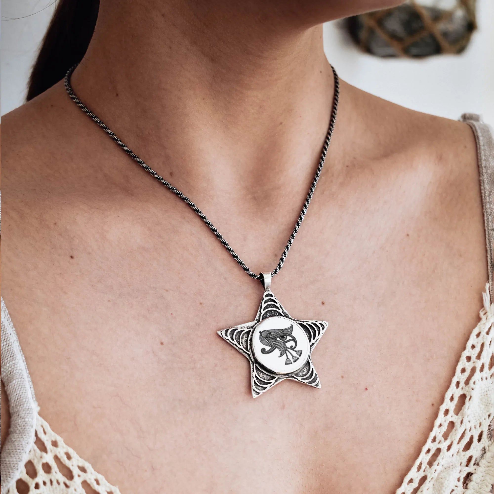 Star-shaped pendant necklace on a person wearing a beige lace top.