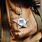 Silver star-shaped pendant with intricate design on a textured fabric background