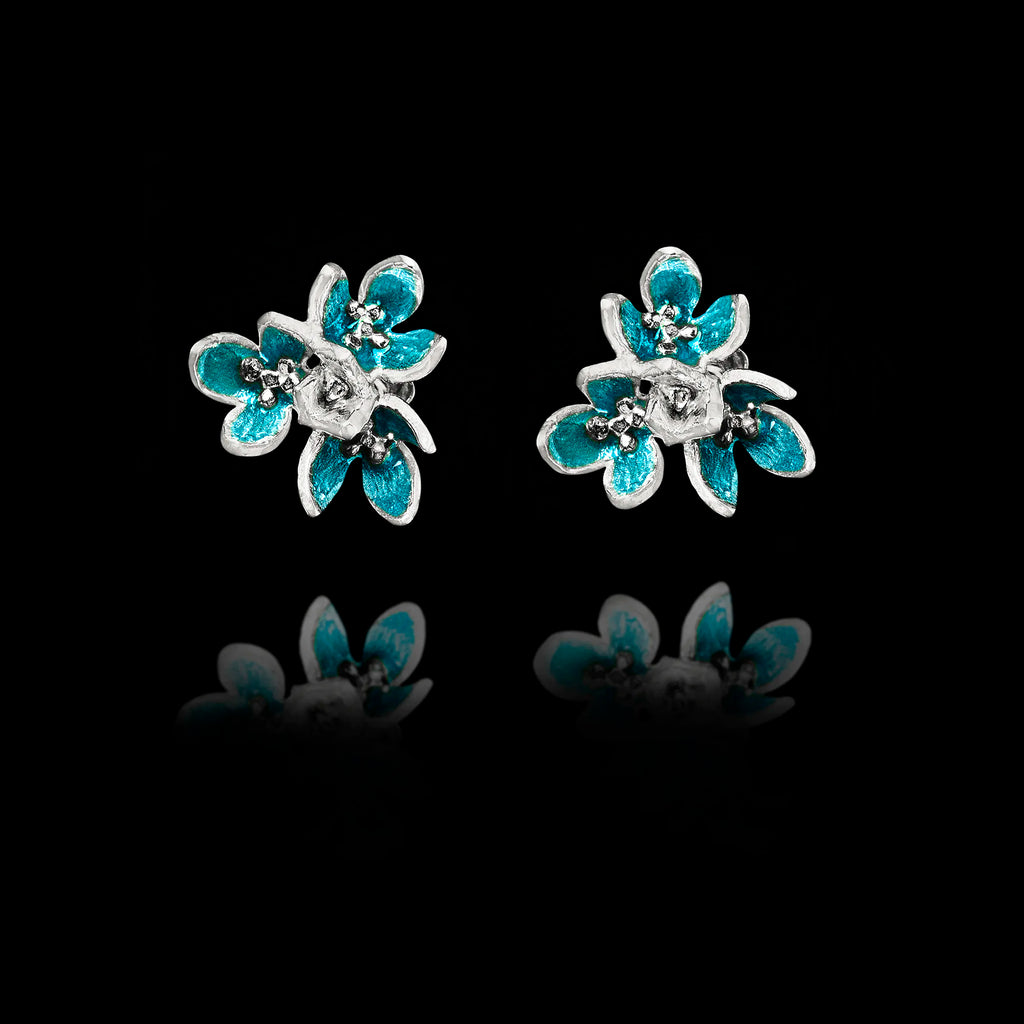 Front view of silver flower stud earrings with layered petals and vibrant turquoise enamel detailing.