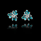 Front view of silver flower stud earrings with layered petals and vibrant turquoise enamel detailing.