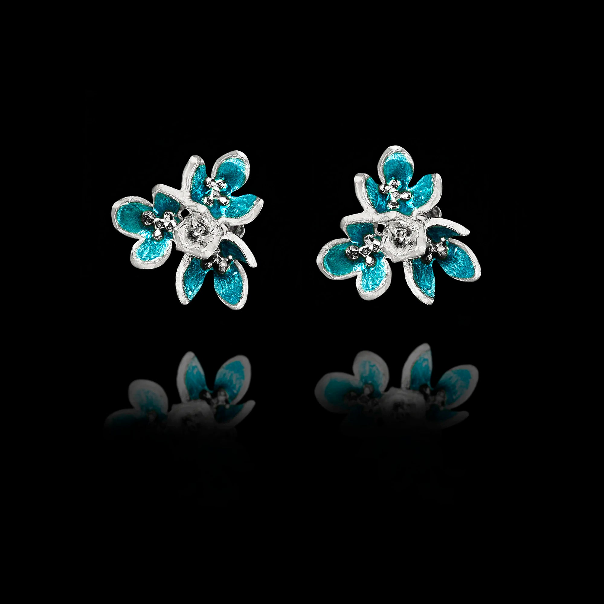 Front view of silver flower stud earrings with layered petals and vibrant turquoise enamel detailing. Main image