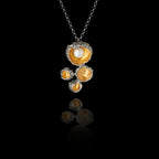 Side angle view of a 925 sterling silver bird's nest pendant showing four organic gold-plated nest forms with rough oxidised silver rims and a freshwater pearl on a silver chain against a black background.