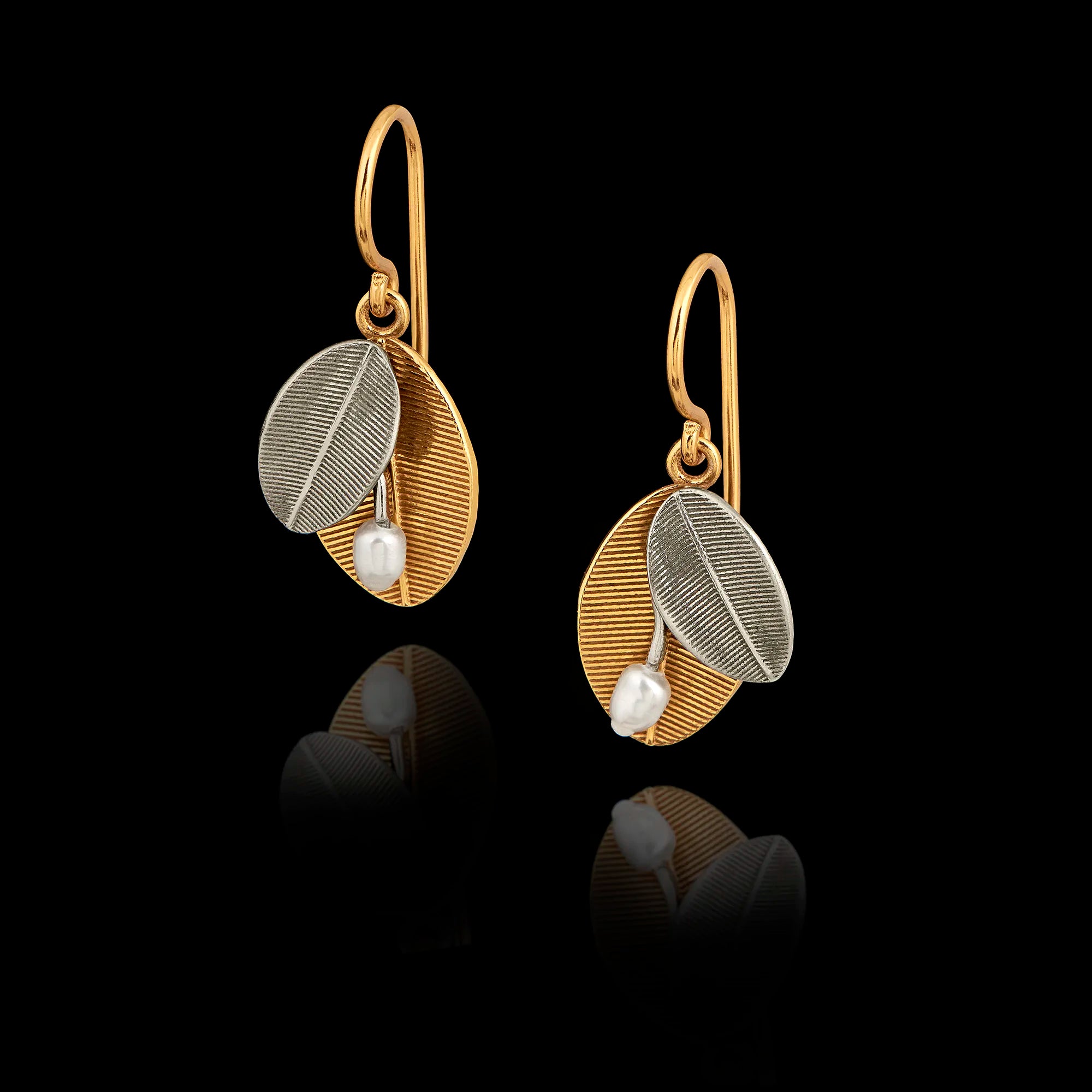 A pair of silver drop earrings featuring one gold textured leaf, one silver leaf, and a small white pearl at the base. Main image