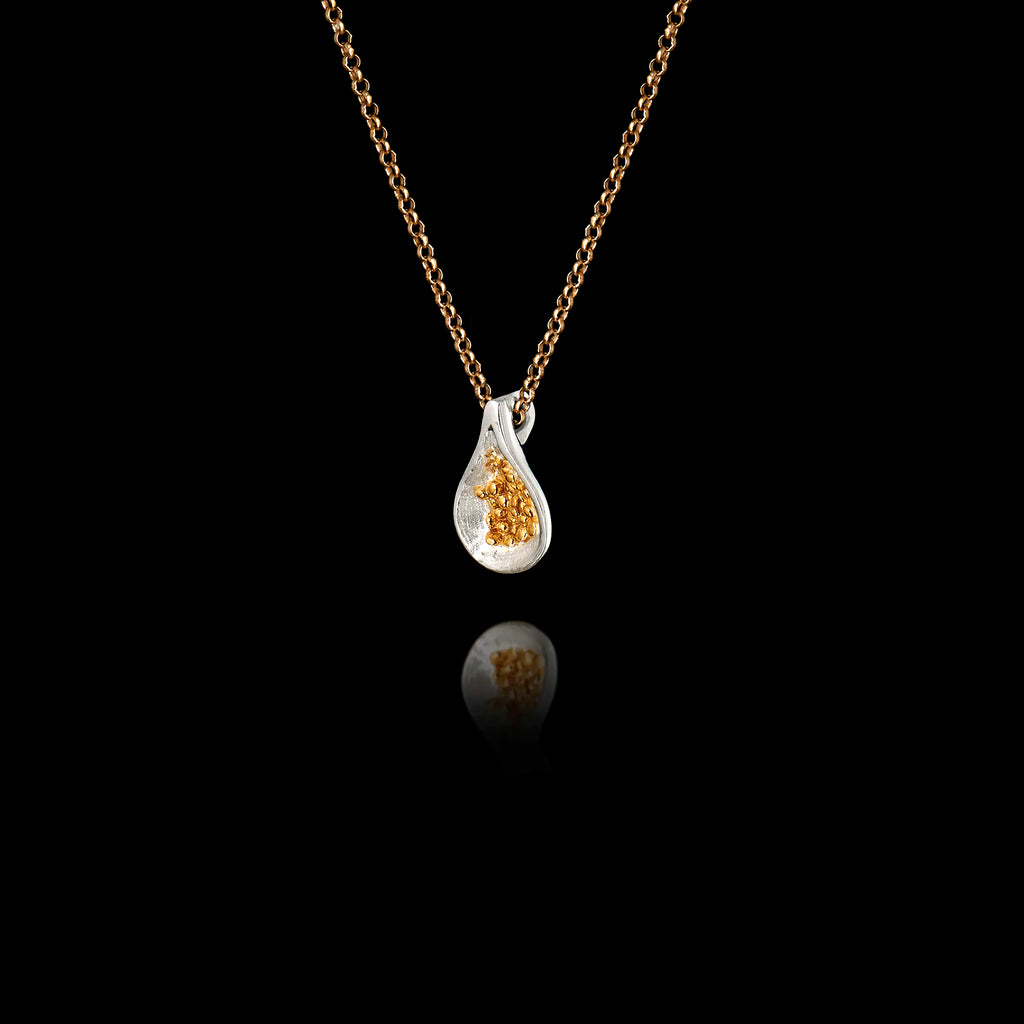 Side angle view of a 925 sterling silver fig pendant showing the smooth rhodium-plated teardrop form and gold-plated granule seed cluster on a gold chain against a black background.
