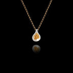 925 sterling silver fig pendant with rhodium-plated teardrop frame and cluster of gold-plated granule seeds inside, hanging on a gold chain against a black background.
