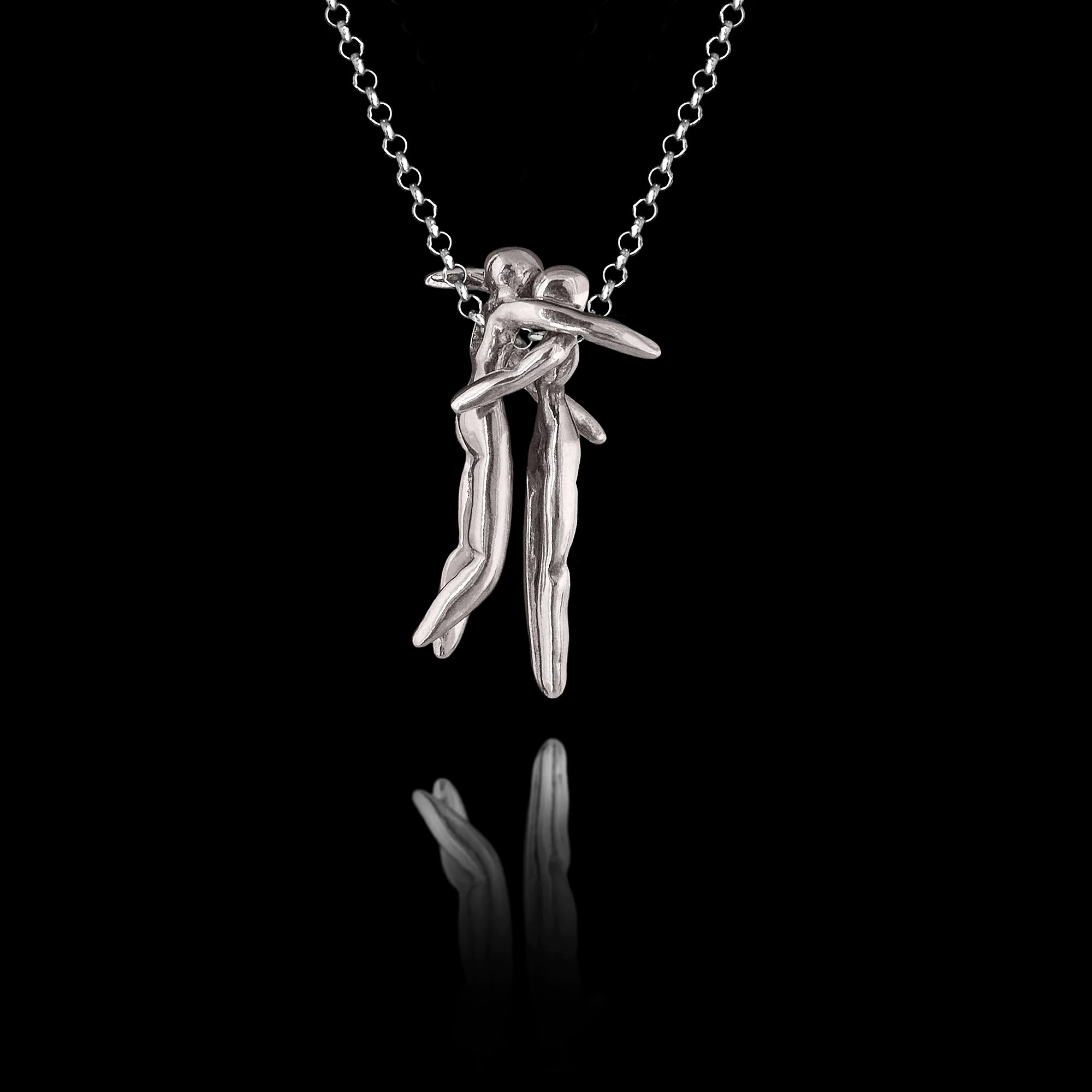 925 sterling silver hug pendant featuring two sculpted human figures in a tender embrace, linked by a small chain, hanging on a silver chain against a black background. Main image