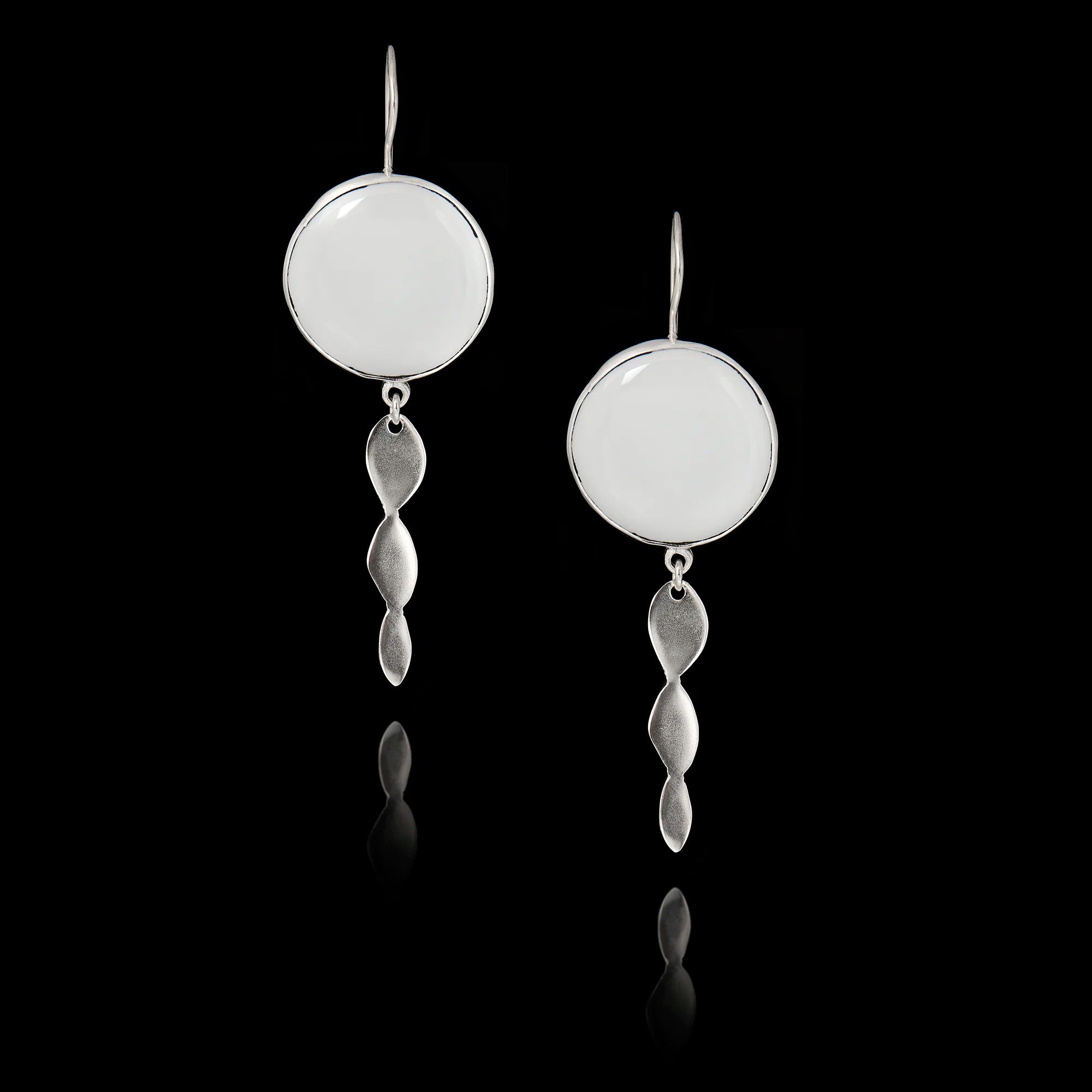 Silver earrings with circular tops and dangling elements on a black background