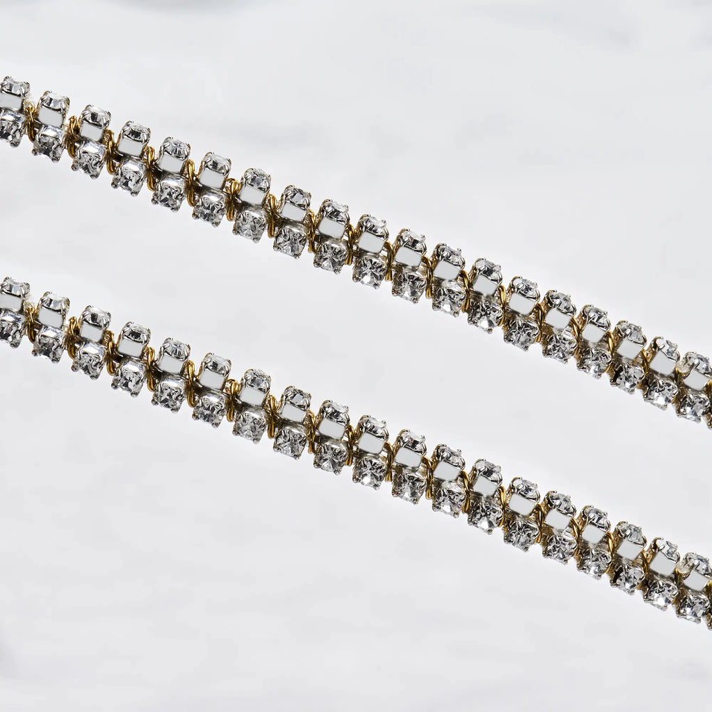 Close-up of sterling silver wedding crowns featuring an intricate gold-plated wire wrap and shimmering white crystals.