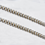 Close-up of sterling silver wedding crowns featuring an intricate gold-plated wire wrap and shimmering white crystals.