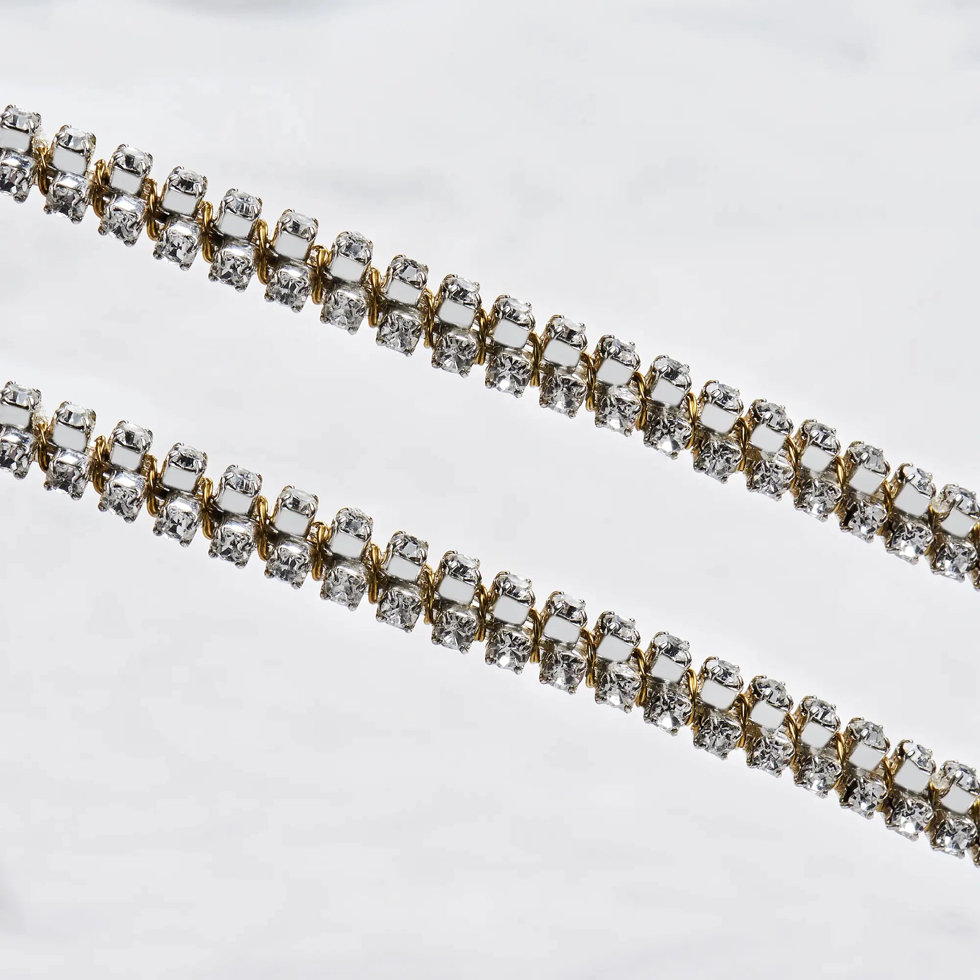 Close-up of sterling silver wedding crowns featuring an intricate gold-plated wire wrap and shimmering white crystals.