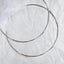 Full view of handmade sterling silver Stefana with triple round wire and white ribbon on a textured background.