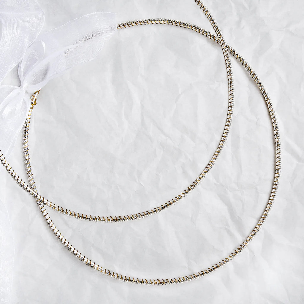 Handmade sterling silver Stefana with gold-plated wire details and white crystals on a white textured background.