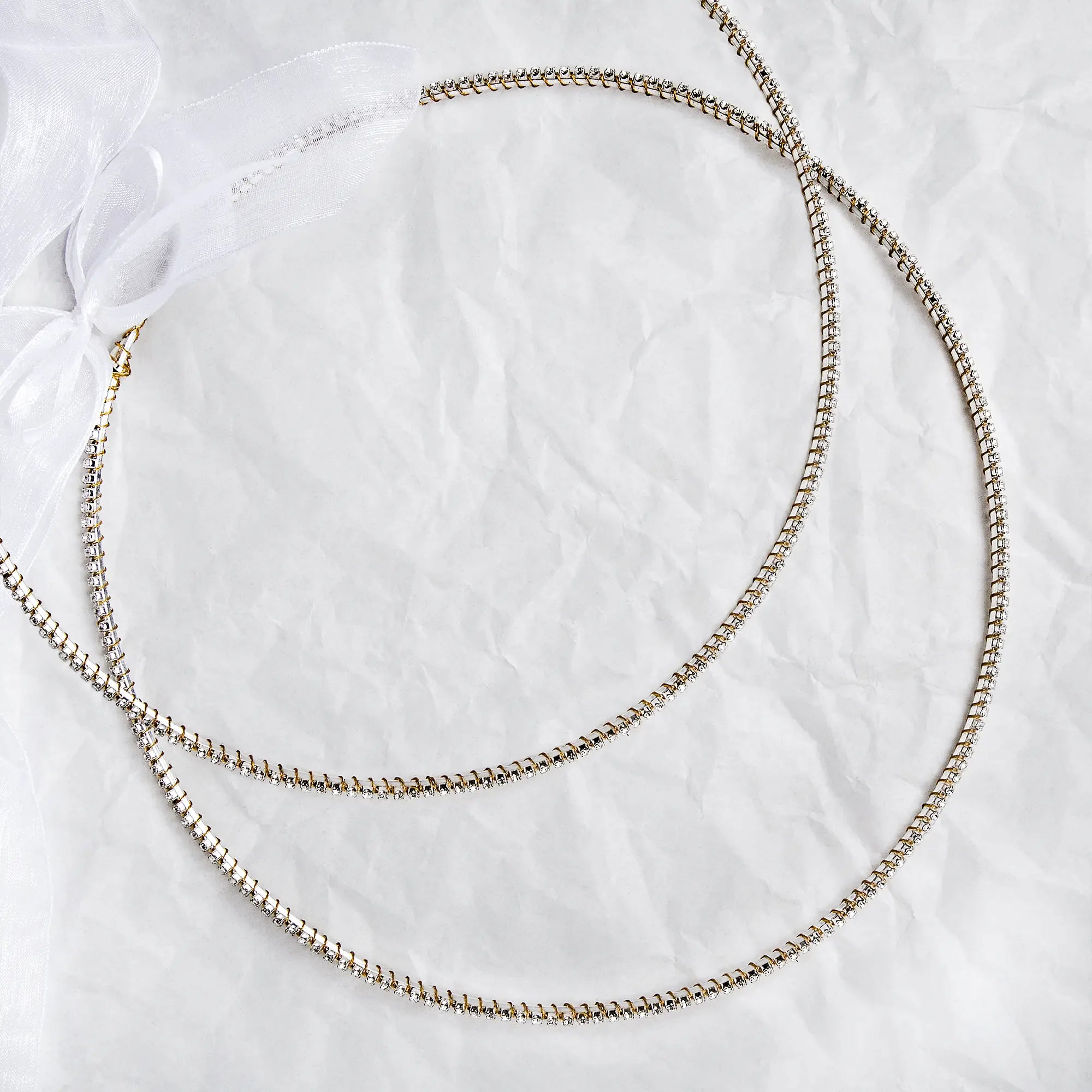 Handmade sterling silver Stefana with gold-plated wire details and white crystals on a white textured background.