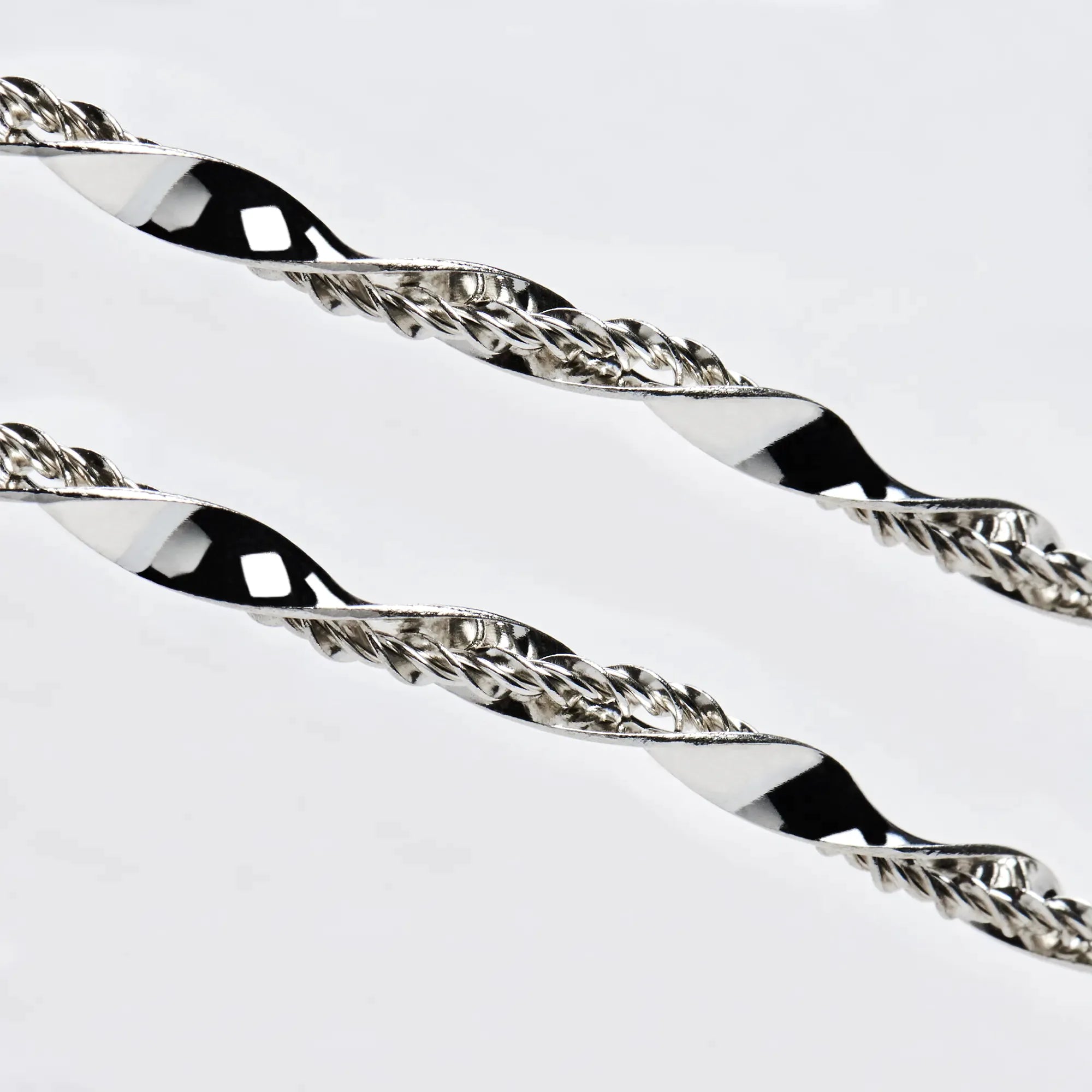 Close-up detail of sterling silver wedding crowns featuring a wide, polished twisted ribbon intertwined with a fine textured wire.