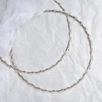 Handmade sterling silver wedding crowns with Spiga chain and Swarovski crystals on white textured background with ribbon.