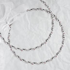 Full view of handmade sterling silver wedding crowns with pink crystals and white ribbon on a white textured background.