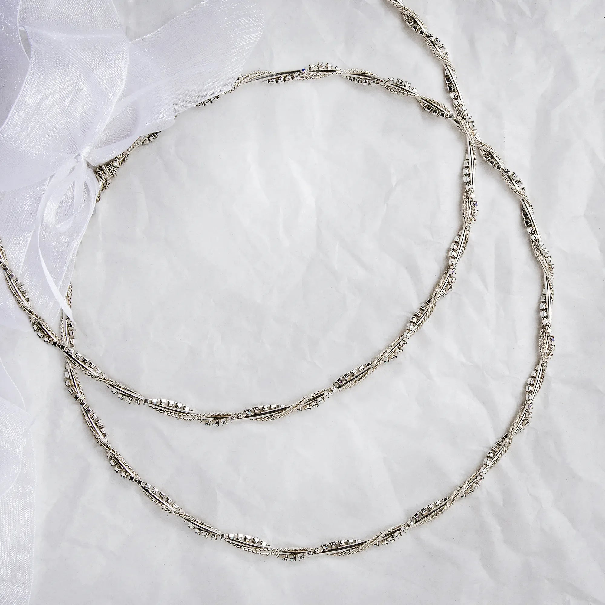 Full view of sterling silver wedding crowns with double twisted wire and multicolored crystals on a white textured background. Main image