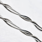 Close-up detail of two thick round sterling silver wires braided together with a delicate twisted wire.