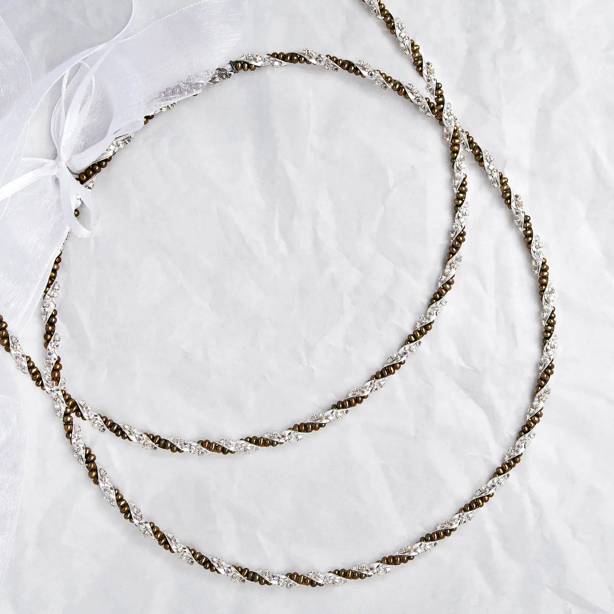 Full view of handmade sterling silver Stefana with gold-toned pearls and colorful crystals on a white textured background. Main image