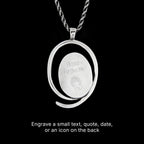 Back side of a silver pendant with engraved text on a black background