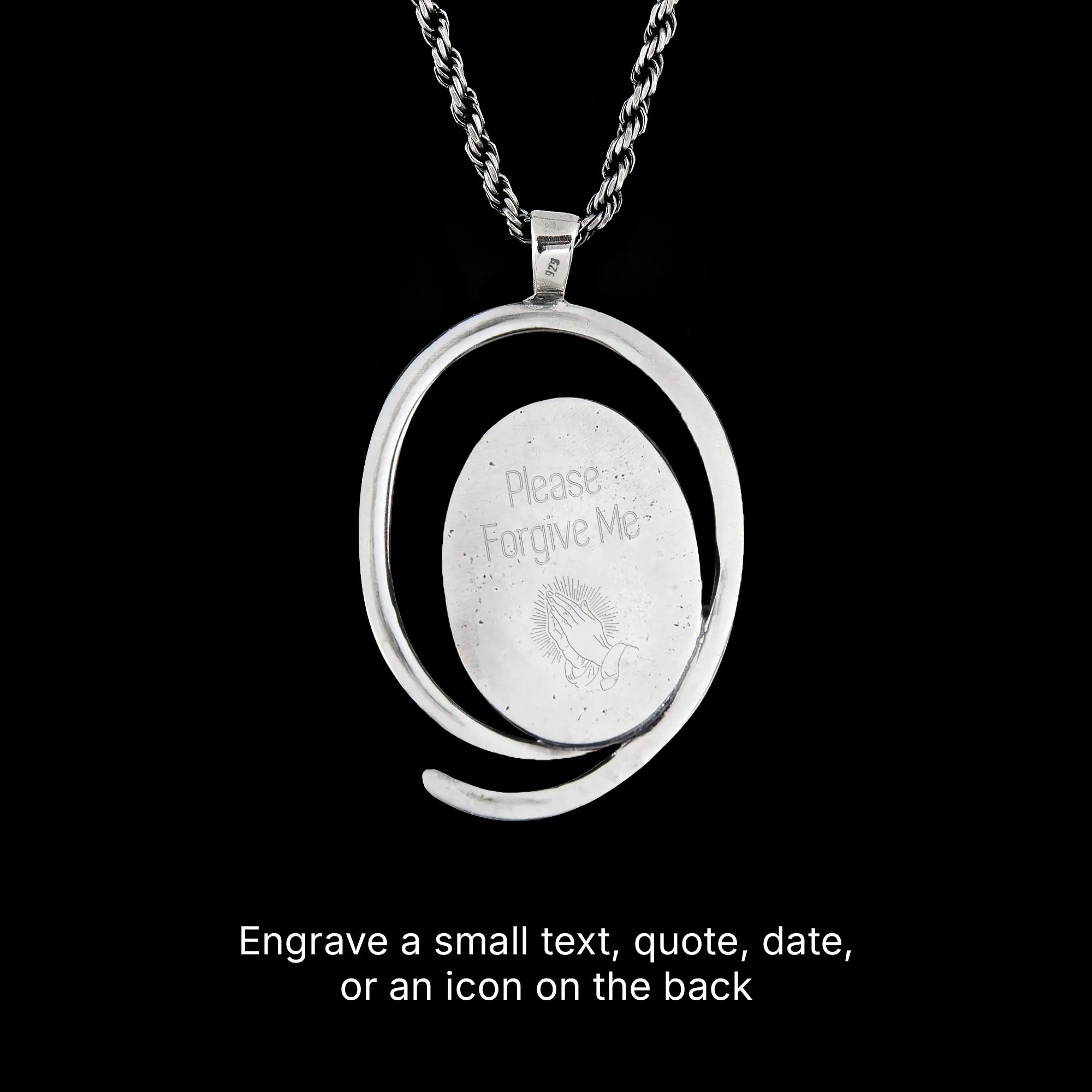 Back side of a silver pendant with engraved text on a black background